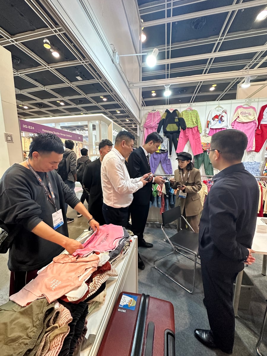Buyers reviewing children's clothing samples with the Yubei Apparel team at the Guangzhou Canton Fair