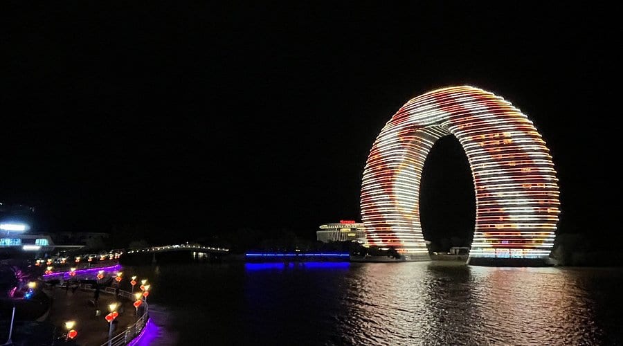 Illuminated horseshoe-shaped lakeside landmark reflected in Taihu Lake at night in Huzhou, China